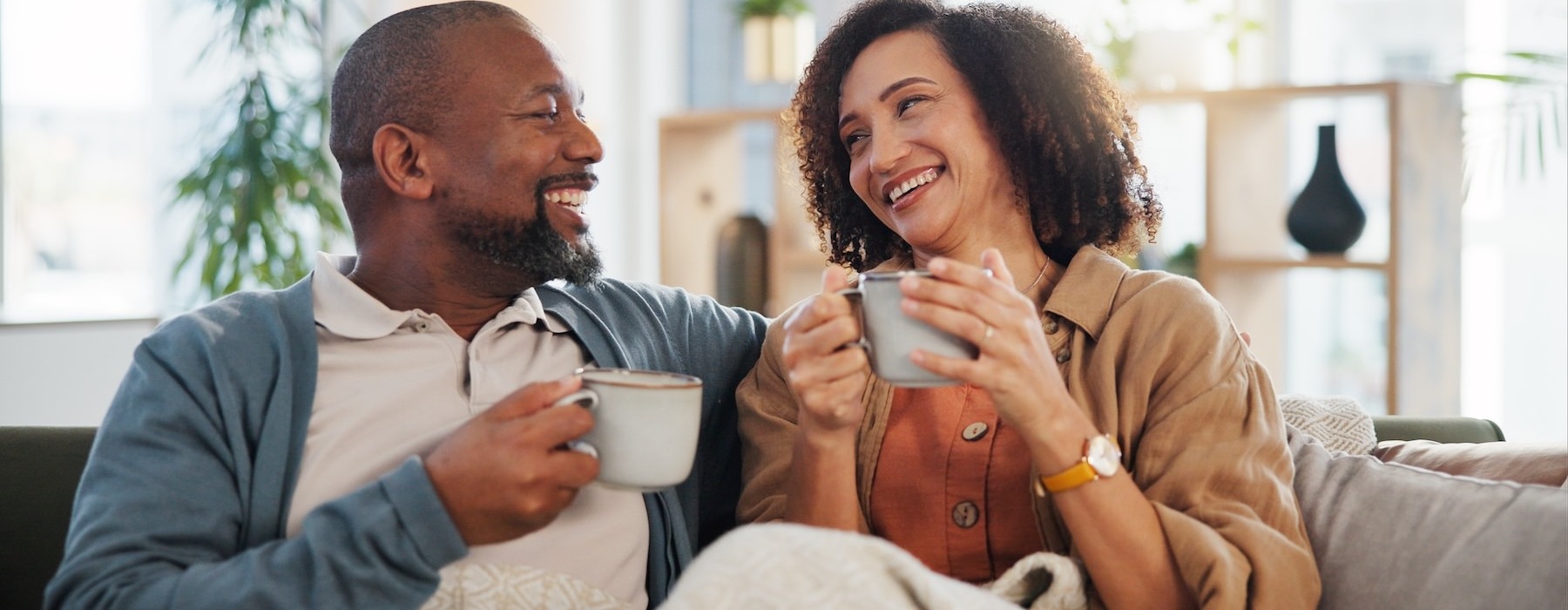 two people sitting on a couch holding cups