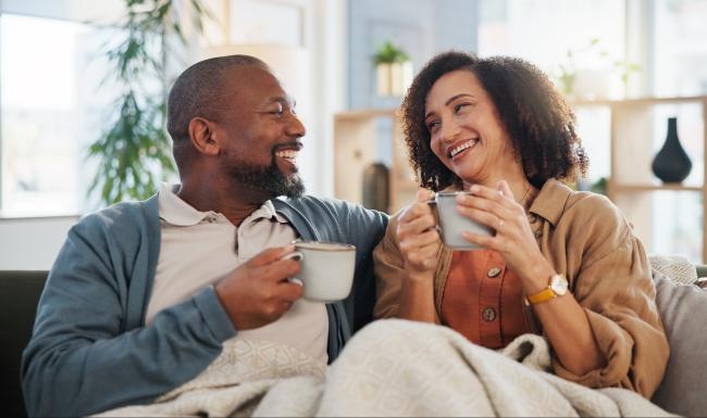 two people sitting on a couch holding cups
